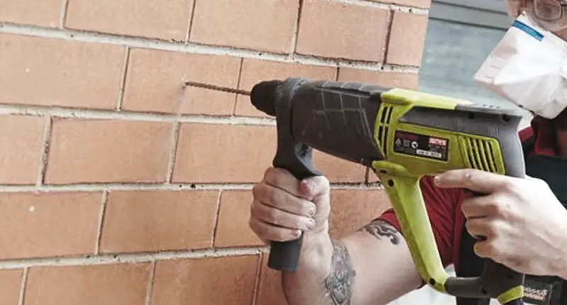 A man drilling into a brick wall