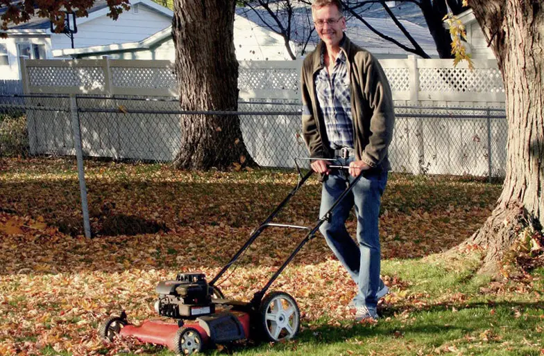 A man with a lawn mulcher mulching leaves