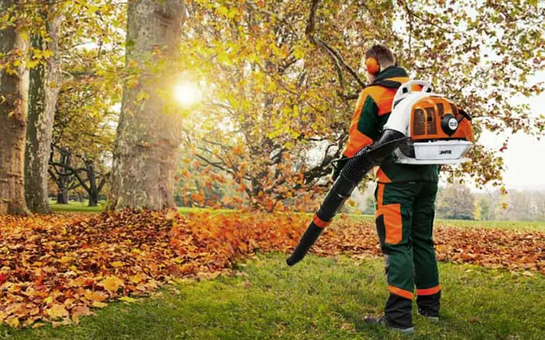 An image of a homeowner using a petrol powered backpack leaf blower