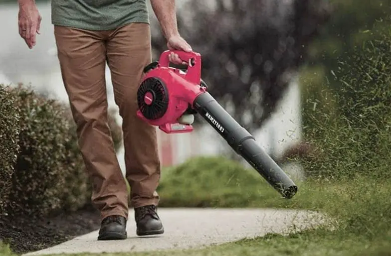 An image showing a homeowner blowing grass cuttings with a leaf blower