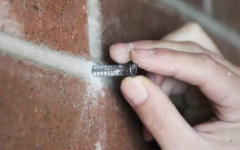 A picture of a wall plug being inserted into brick